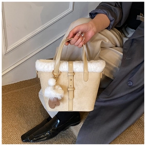 Detail of beige faux shearling bucket bag with heart charm and gold buckle accents