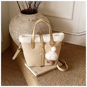 Detailed close-up of beige suede bucket bag with white faux fur trim and heart charm