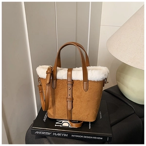 Detail of brown faux suede bucket bag with plush white faux fur trim and leather handle