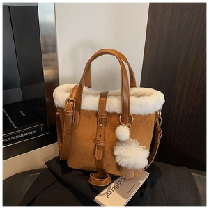 Detail of brown suede bucket bag with white faux fur trim and dual plush pom-pom charms