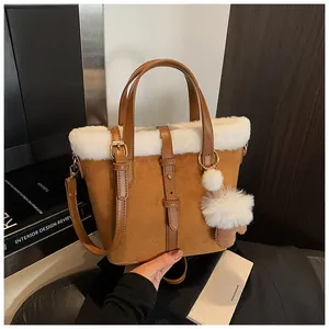 Detail of faux shearling trim on a brown frosted suede bucket bag with leather strap