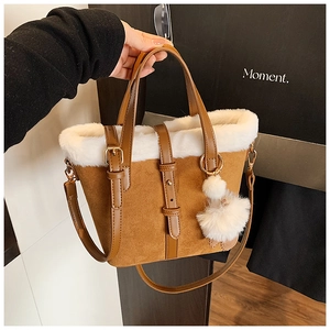 Detail of winter bucket bag with brown suede texture and white faux fur trim and pompom