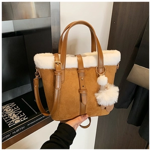 Detail of brown faux suede bucket bag with white fleece trim and furry pom-pom charm