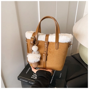 Detail of a brown frosted leather bucket bag with white faux fur trim and furry charm