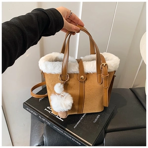 Close-up of brown suede bucket bag with white faux fur trim and gold metal buckles