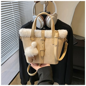 Close-up of beige suede bucket bag featuring white faux fur trim and cute glove charm