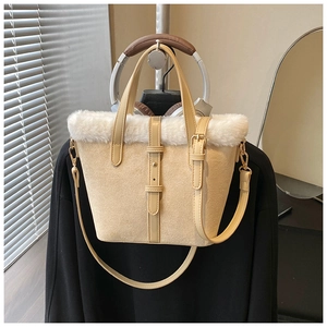 Detail of beige suede bucket bag featuring faux fur trim and gold buckle hardware
