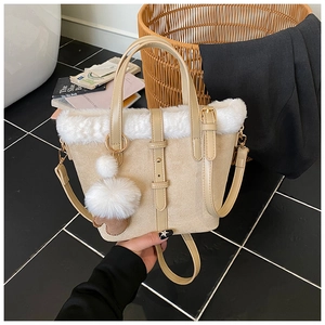 Detailed view of beige suede bucket bag featuring white faux fur trim and pompom detail