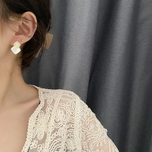 Elegant geometric gold drop earrings with white mother-of-pearl squares on a female model