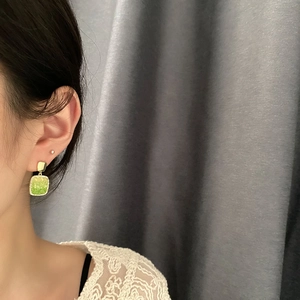 Elegant gold-framed green square stone drop earrings shown on model with retro style
