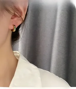 Close-up of gold hoop earring with colorful rectangular zircons on model ear