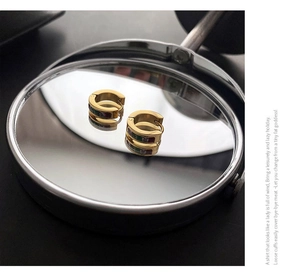 Detail of gold titanium steel hoops with green zircon pendants and colorful enamel inlay
