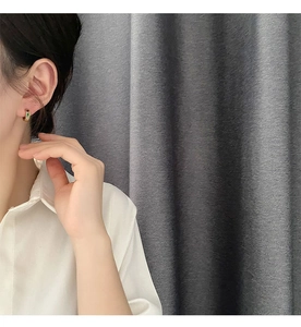 Detailed view of gold hoop earrings with green zircon pendants worn by a model