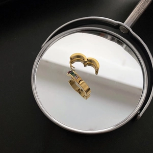 Gold-plated stainless steel hoop earrings with colorful gemstones on a mirror