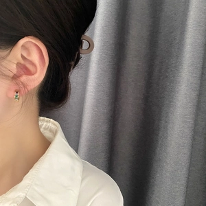Golden huggie hoop earrings featuring multi-colored square zircon stones on model
