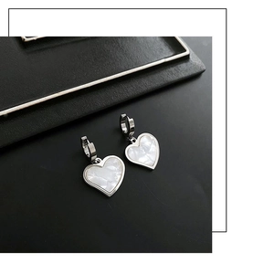 Detail of silver heart earrings with white mother of pearl inlay on black display tray