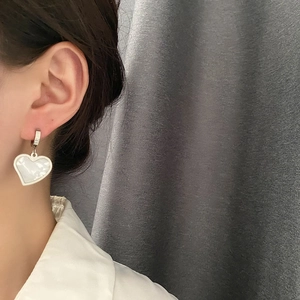 Silver heart earrings with iridescent mother of pearl inlay worn on earlobe