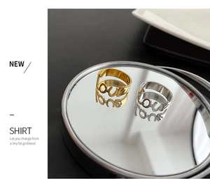 Dettaglio di anelli con scritta 'love' oro e argento riflessi su una superficie a specchio