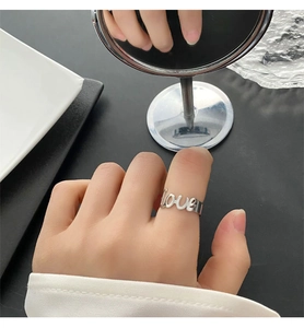 Dettaglio macro di un anello con lettera 'love' traforata in argento lucido al dito
