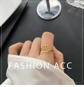 Macro detail of gold cat paw cut-out ring on hand with elegant lifestyle backdrop