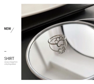 Close-up of silver cat paw design ring with hollow pad detail on a mirror surface