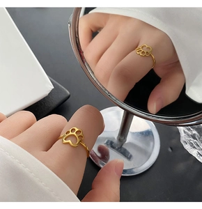 Macro detail of gold cat paw cut-out ring with artistic reflection in a mirror