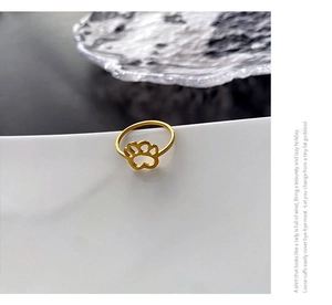 Detail view of a gold-plated cat paw cutout ring on a minimalist jewelry stand