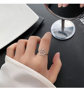 Close-up of a silver hollow cat paw ring on a model finger showing dainty cute details