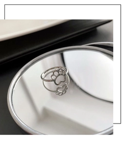 Macro shot of a cat paw cutout ring on a mirrored surface with elegant reflection