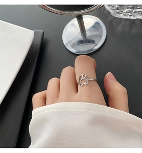 Close-up of a polished titanium steel ring with a hollow cat paw design on finger