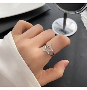 Close-up of minimalist silver hollow star ring worn on finger for a stylish jewelry look