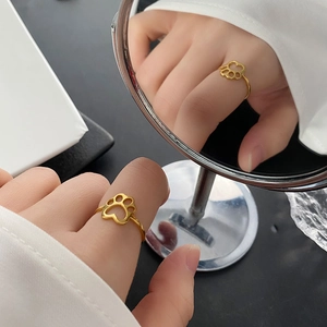 Luxury gold titanium steel cat paw open ring displayed on a reflective mirror surface
