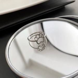 Minimalist silver cat paw cutout ring in titanium steel on a reflective mirror surface