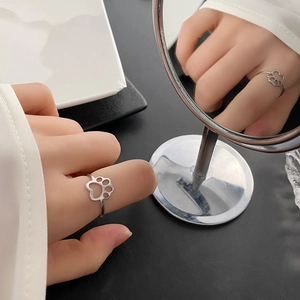 Minimalist silver cat paw print ring in stainless steel worn on finger with mirror reflection