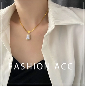 Close-up of golden blade chain necklace with rectangular shell inlay pendant on model