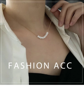 Close-up of minimalist gold chain necklace with white pearl beads on collarbone