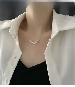 Elegant beaded pearl necklace on model featuring nine white beads with thin gold chain