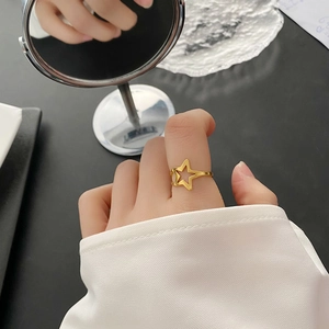Minimalist gold hollow star ring with an open adjustable band worn on a hand