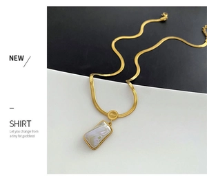 Macro detail of gold blade chain featuring a pearl inlay pendant and Love engraving