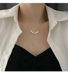 Detail of beaded pearl necklace with nine white beads on a slim gold chain for women