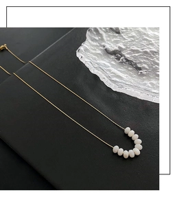 Detailed view of elegant gold beaded necklace with white pearls on a glass tray