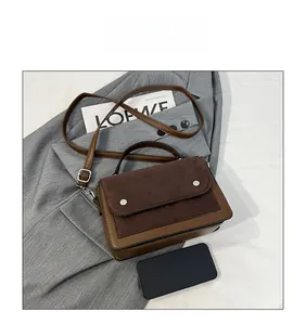 Close-up of retro color-block handbag with brown suede flap and silver stud accents