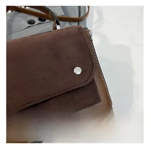 Close-up of brown suede patchwork handbag featuring a round metal magnetic snap button