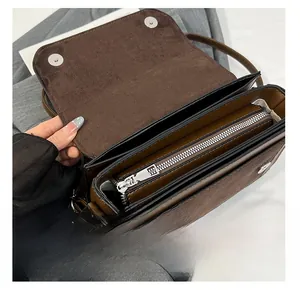 Detail of interior compartments and silver magnetic closure of the brown crossbody bag