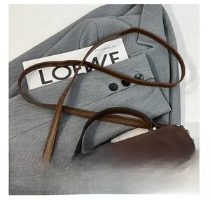 Close-up of adjustable strap and brown suede texture on a vintage crossbody bag