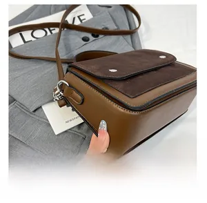 Detail of a brown two-tone crossbody bag featuring a suede flap and silver magnetic buckle
