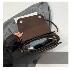 Interior view of brown faux suede shoulder bag showing storage for phone and cosmetics