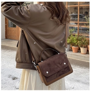 Close-up of contrast brown crossbody bag worn with leather jacket in winter snow setting