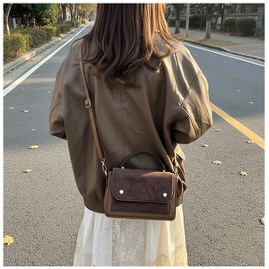 Detail of color-block brown crossbody bag with silver hardware on a street model
