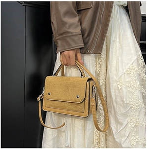 Detail of contrast stitching mustard yellow handbag with matte leather lid and silver studs